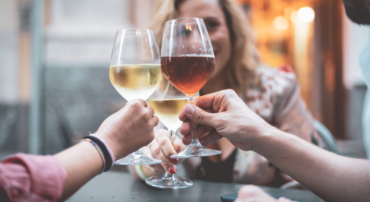 Ist Wein vegan: drei Freunde stoßen mit Wein an.