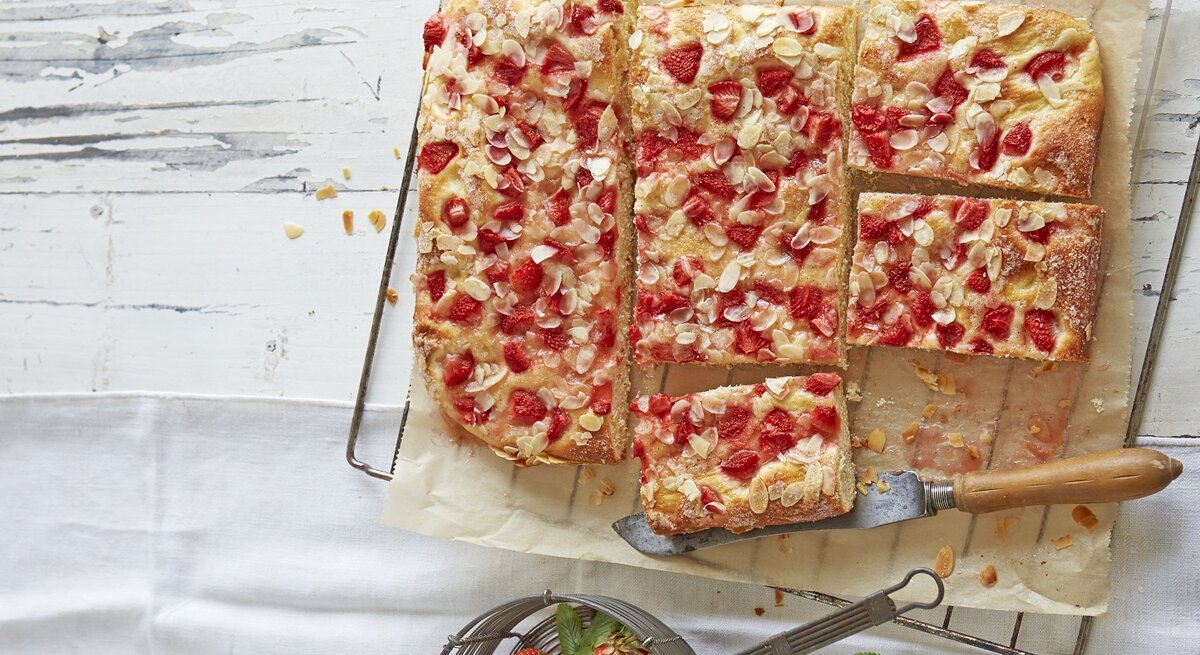 Der Kuchen auf einem hellen Holzbrett und hellem Tisch in Stücke geschnitten. Alles direkt von oben fotografiert.