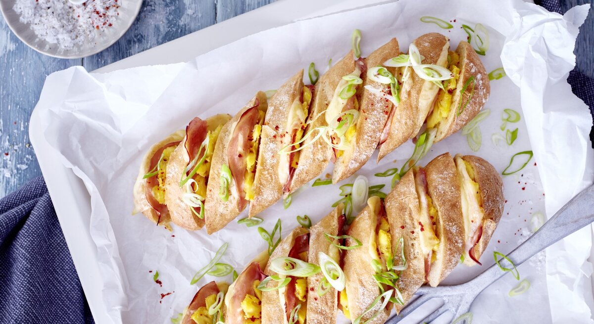 Hasselback-Baguette Hawaii auf einem Backblech mit weißem Backpapier.