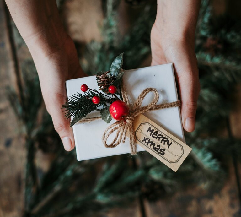 Eine Person hält ein verpacktes Geschenk in der Hand. | © Getty Images/ Svante Berg / EyeEm