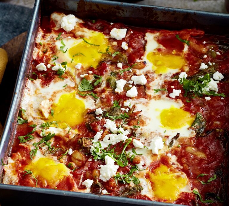 In einer Auflaufform ist ein Ofen-Shakshuka mit Spinat angerichtet. Es ist mit Petersilie bestreut.  | © EAT CLUB / Isabell Triemer