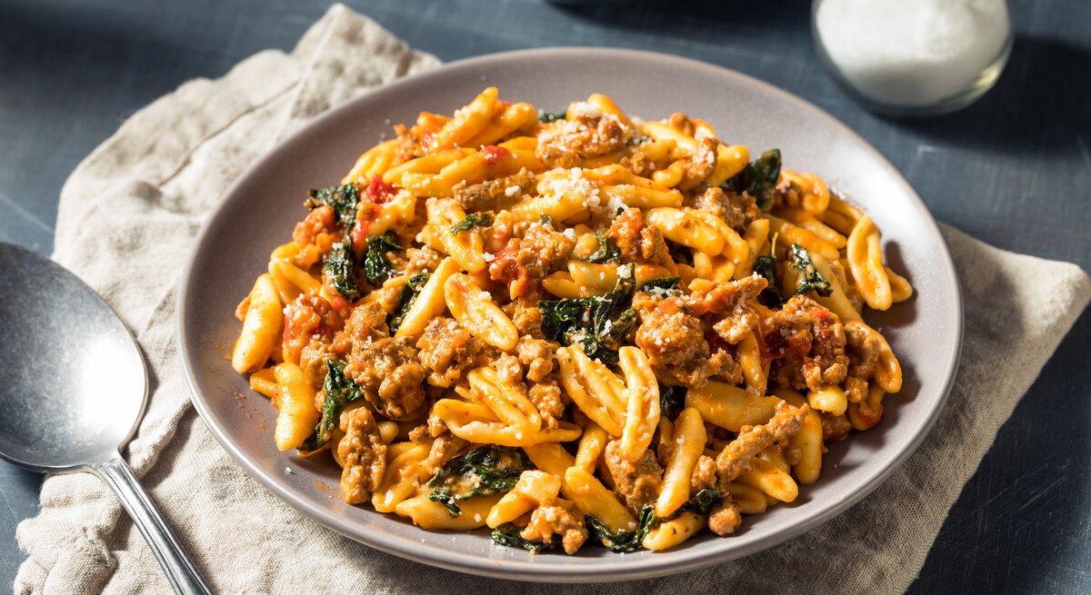 Pasta in tomatiger Hackfleisch-Schmand-Soße auf weißem Teller. 