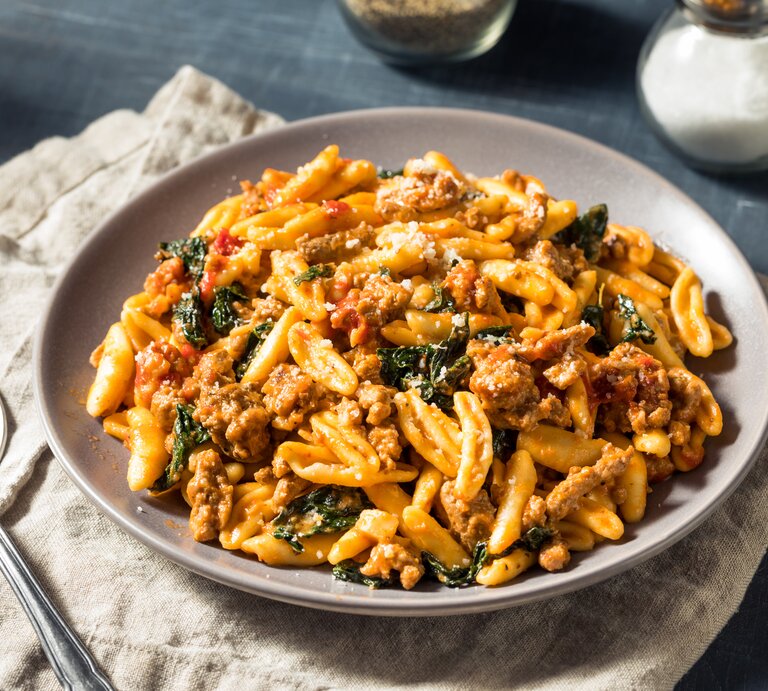 Pasta in tomatiger Hackfleisch-Schmand-Soße auf weißem Teller.  | © Getty Images/bhofack2