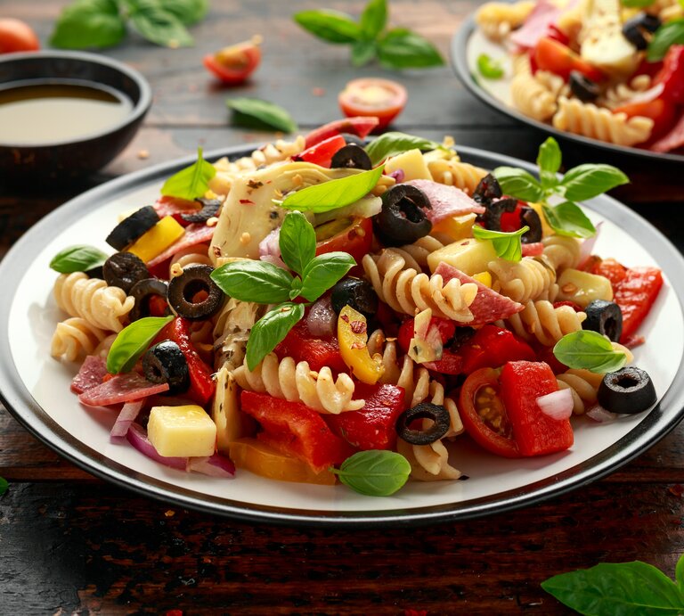 Antipasti-Nudelsalat mit Artischocken, Oliven, Salami, Käse und Basilikum. | © Getty Images/ DronG