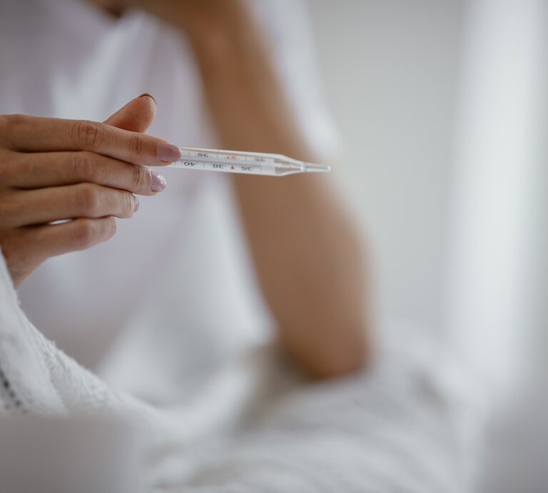 Eine Hand hält ein Fieberthermometer  | © iStock.com/Milos Dimic
