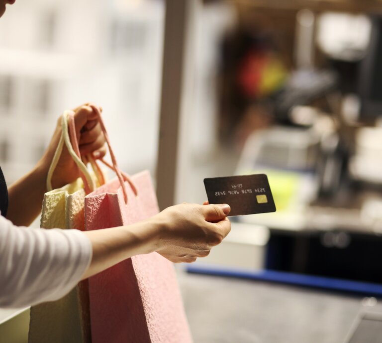 Ein Frauenarm, der Shoppingtüten und eine Kreditkarte hält | © IMAGO / imagebroker