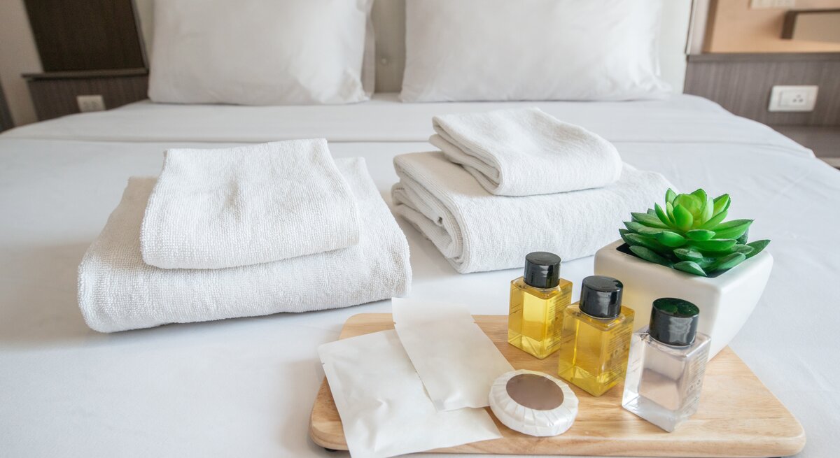 Shampoo-Proben liegen schön dekoriert auf dem Hotelbett.