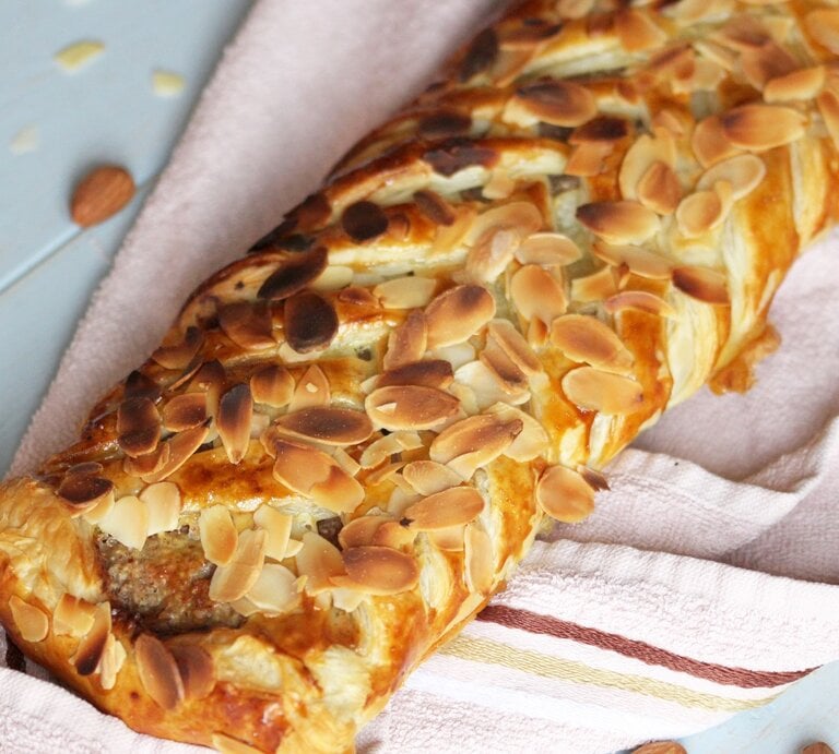 Ein Marzipan-Mandel-Strudel auf einem hellen Tisch mit rosa Tischdecke. Alles von schräg oben fotografiert. | © Shutterstock/ Joanna 12