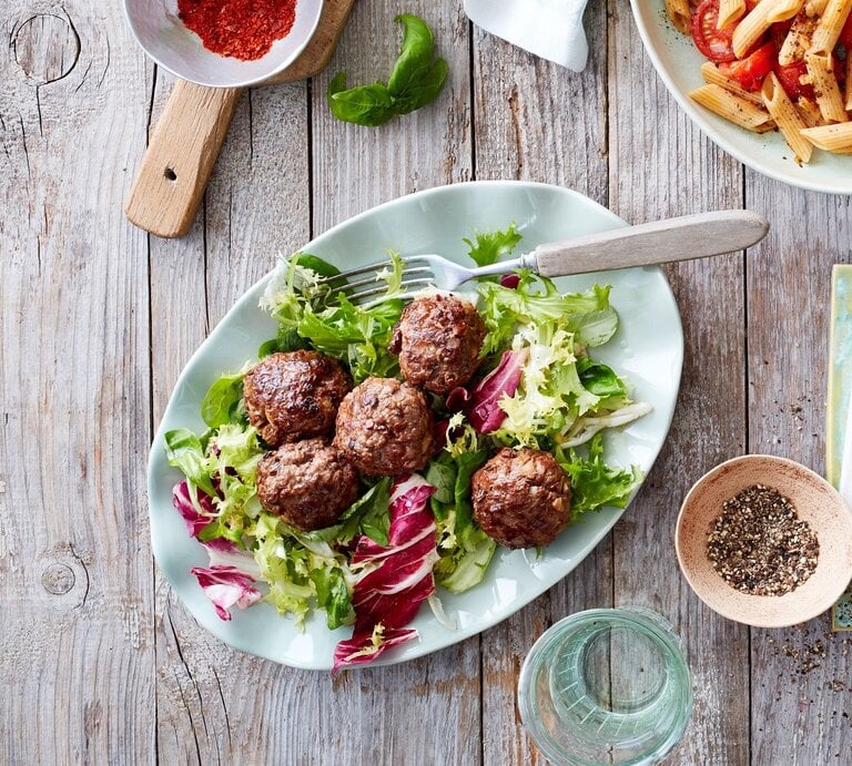 Auf einem Teller ist eine Portion Aroma-Bällchen angerichtet. Sie werden mit Salat seviert. | © EAT CLUB / Isabell Triemer