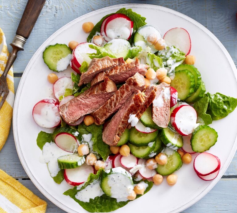 Auf einem Teller ist ein Zaziki-Salat mit Steakstreifen angerichtet. Er ist mit Radieschen und Gurke verfeinert. | © EAT CLUB / Isabell Triemer
