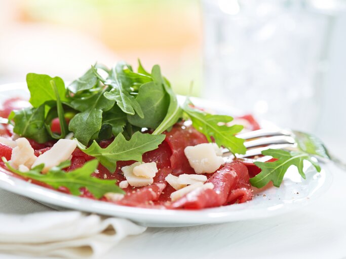Seitenansicht auf einen weißen Teller belegt mit Rinder-Carpaccio | © iStock/ Moncherie