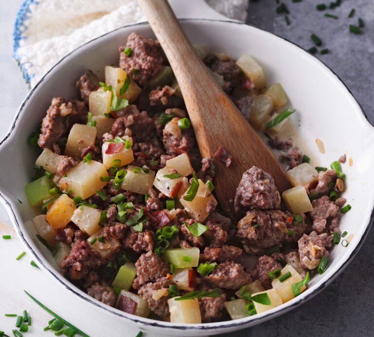Draufsicht: Eine  weiße Hackfleischpfanne mit Kohlrabi. In dem Essen steckt ein großer Löffel aus Holz. | © StockFood/Gräfe & Unzer Verlag/Kramp + Gölling