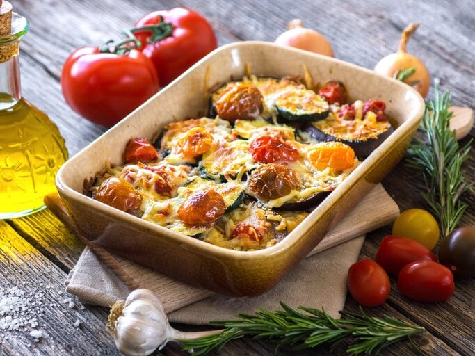 Eine Ofenform mit dem Gericht auf einem rustikalen Tisch. | © iStock/zeleno