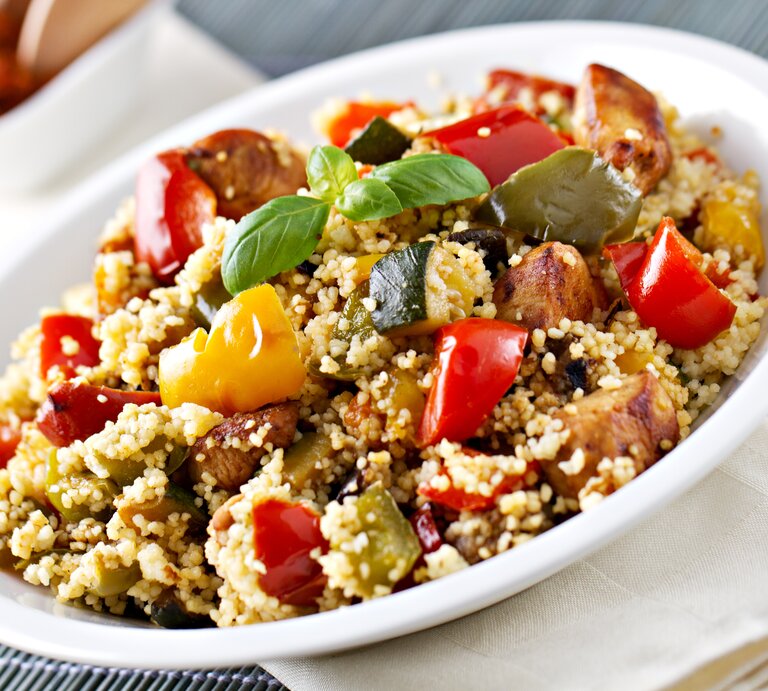 Weißer Teller, darauf Couscous-Salat mit Gemüse und Hähnchen. | © iStock/svariophoto