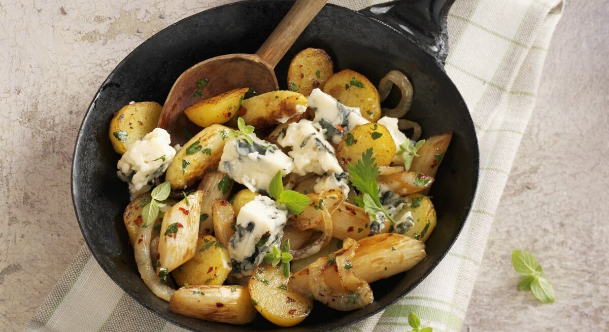 Draufsicht: eine Kartoffel-Spargel-Pfanne mit Roquefort auf einem Küchentuch.