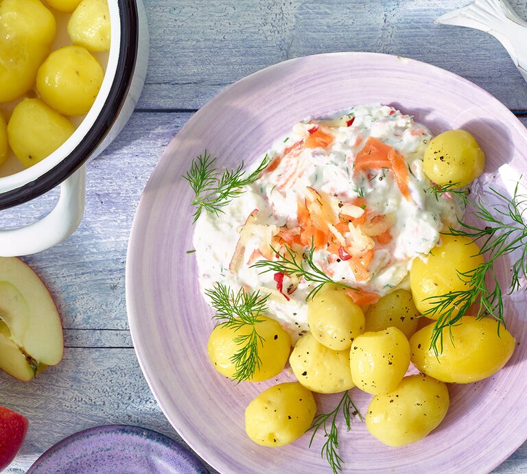Draufsicht: Auf einem Tisch, ein runder Teller mit gekochten Kartoffeln und einer Quark-Creme mit Lachs. | © Matthias Liebich
