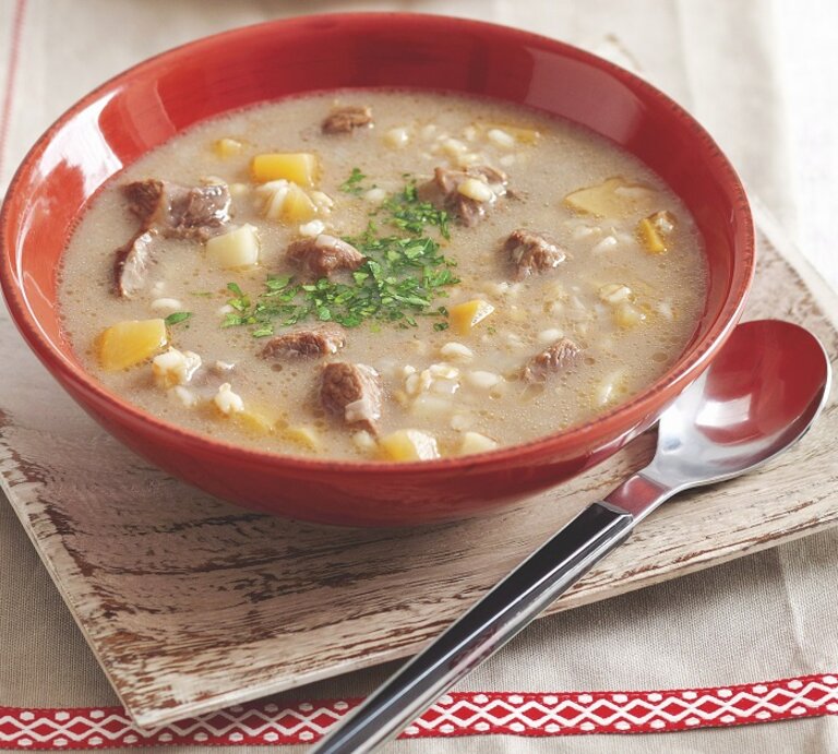 Graupensuppe in rundem Teller / Löffel / Untergrund Holzschlale auf Tisch  | © StockFood / Bauer Syndication