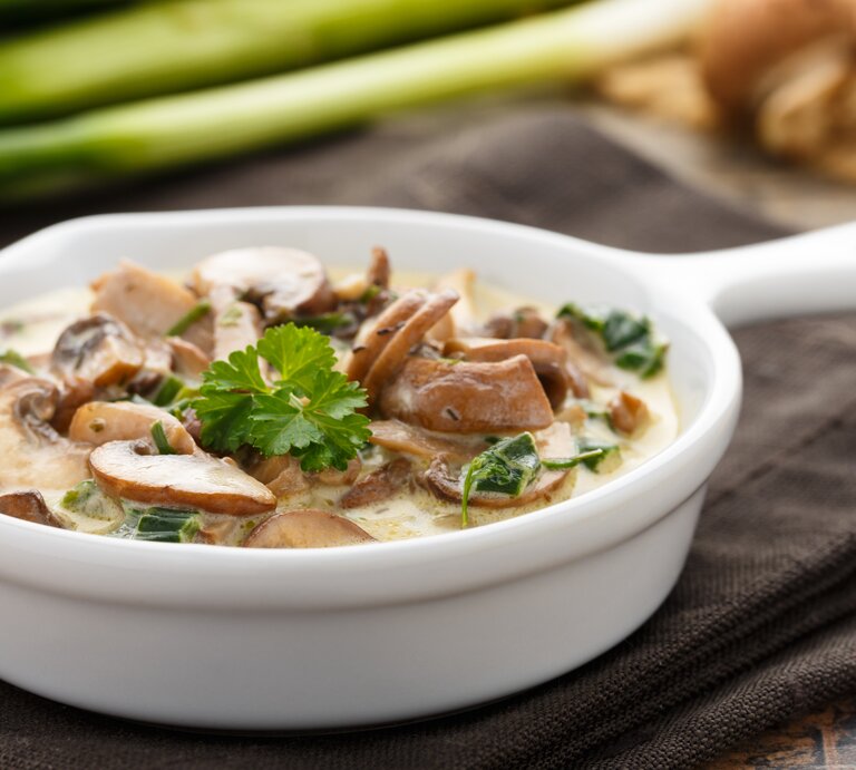 Champignons in Sahnesoße in einer kleinen, weißen Pfanne.  | © iStock/ vertmedia