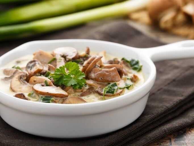 Champignons in Sahnesoße in einer kleinen, weißen Pfanne.  | © iStock/ vertmedia