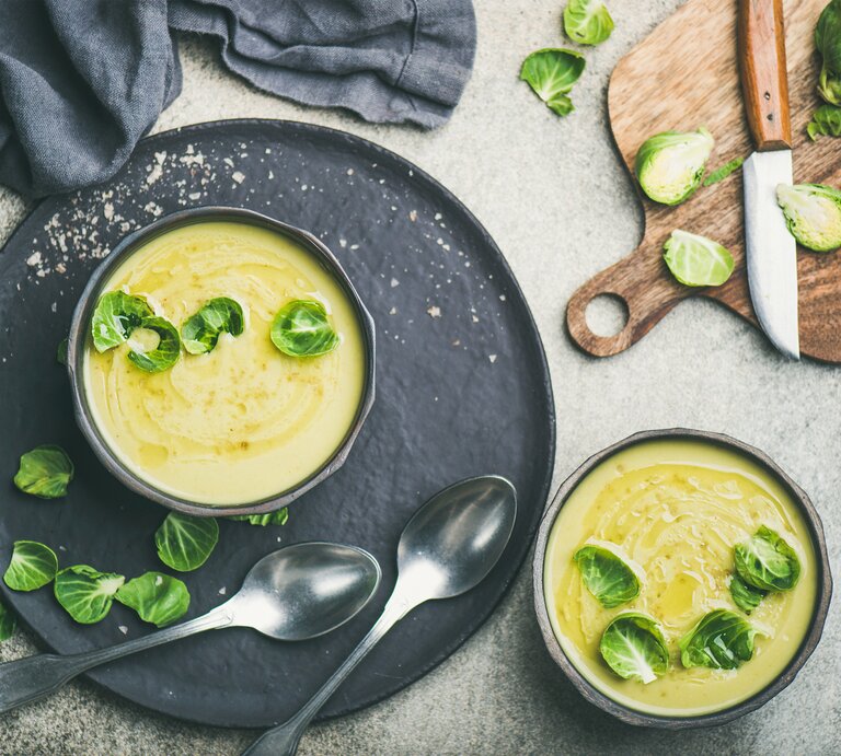 Draufsicht auf eine runde Schüssel gefüllt mit einer cremigen Suppe aus Rosenkohl. Das Ganze steht auf einem runden untersetzer.  | © iStock/Foxys_forest_manufacture