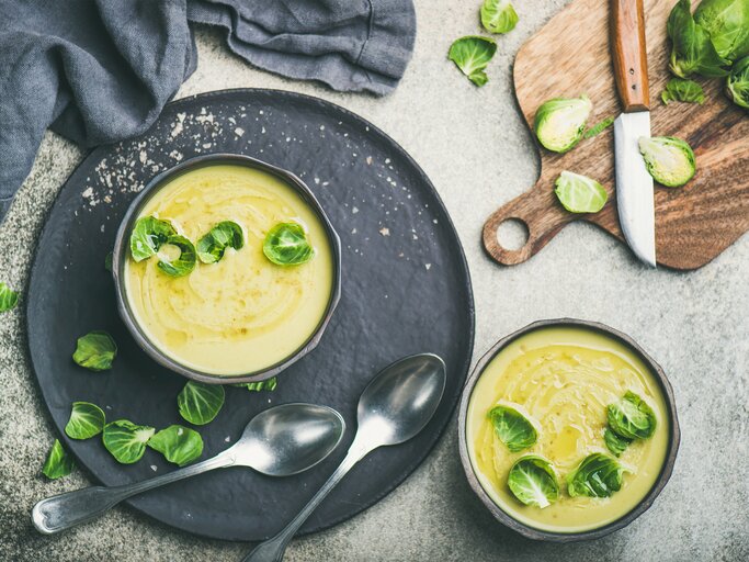 Draufsicht auf eine runde Schüssel gefüllt mit einer cremigen Suppe aus Rosenkohl. Das Ganze steht auf einem runden untersetzer.  | © iStock/Foxys_forest_manufacture