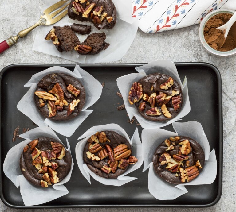 Die Schokomuffins mit Avocado und Nüssen auf einem Blech und grauem Tisch. Alles direkt von oben fotografiert. | © StockFood / ZS Verlag / Speck, Sabrina