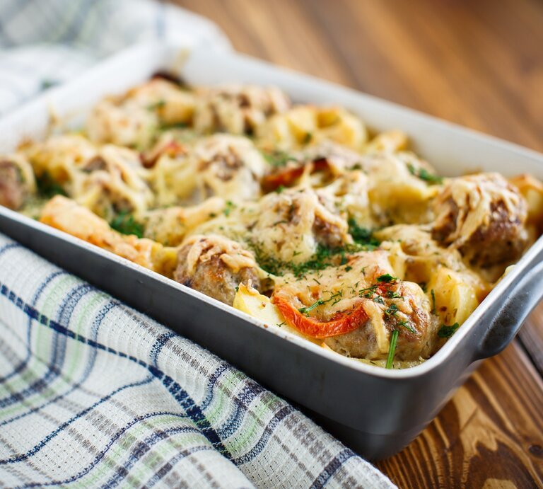 Auflauf mit Kohlrabi und Hackfleisch in einer Auflaufform auf einem Geschirrtuch auf hölzernem Hintergrund.  | © iStock/peredniankina