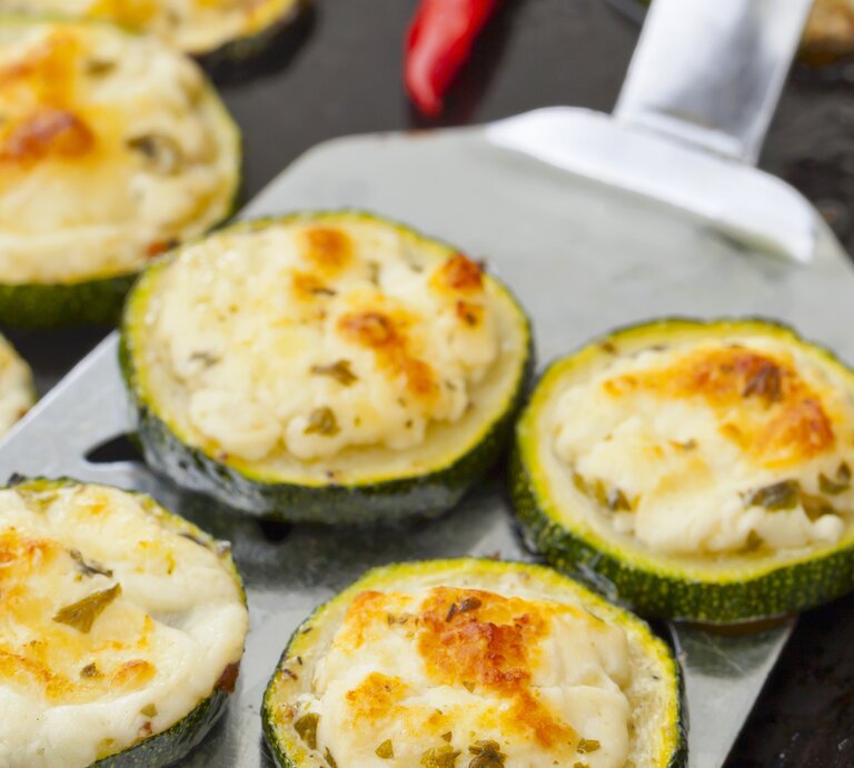 Zucchinischeiben mit Feta auf einem Blech.  | © StockFood