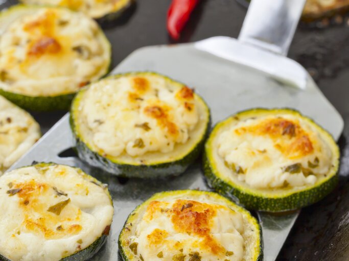 Zucchinischeiben mit Feta auf einem Blech.  | © StockFood