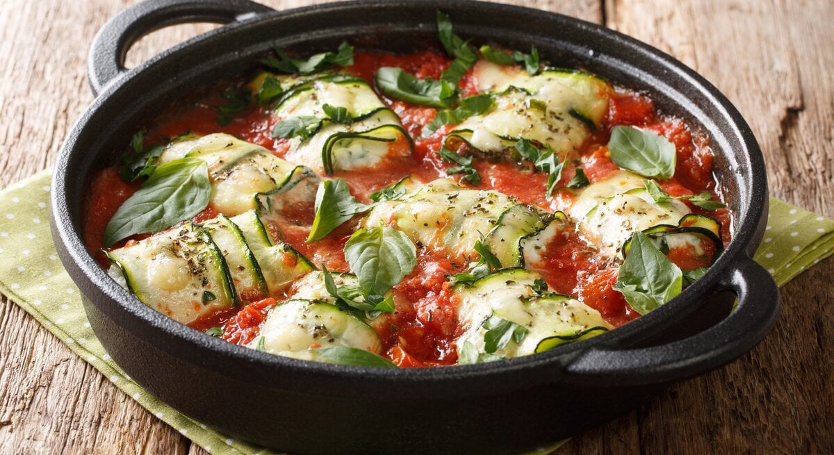 schwarze gusseiserne Pfanne gefüllt mit Zucchini, Feta und Tomatensoße. 