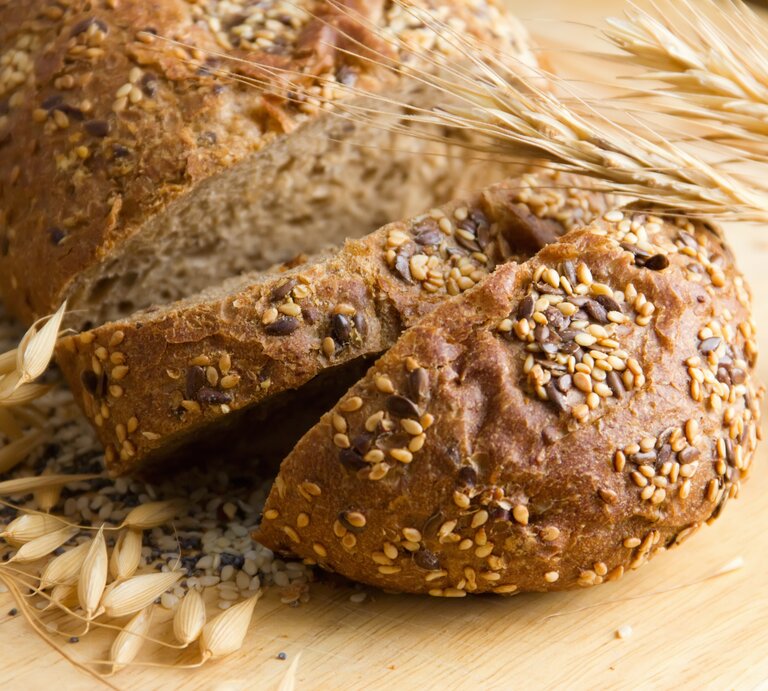 Das Proteinbrot auf einem hellen Schneidebrett nahe und mit frischem Getreide als Dekoration fotografiert. | © iStock/lutavia