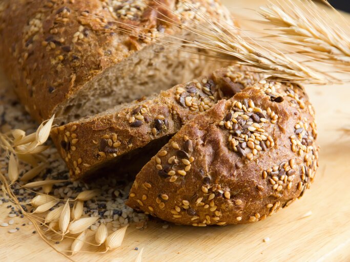 Das Proteinbrot auf einem hellen Schneidebrett nahe und mit frischem Getreide als Dekoration fotografiert. | © iStock/lutavia