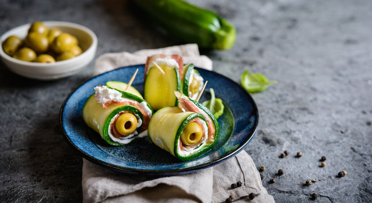 Gerollte Zucchini gefüllt mit Oliven, Schinken und Käse, fixiert mit einem Zahnstocher