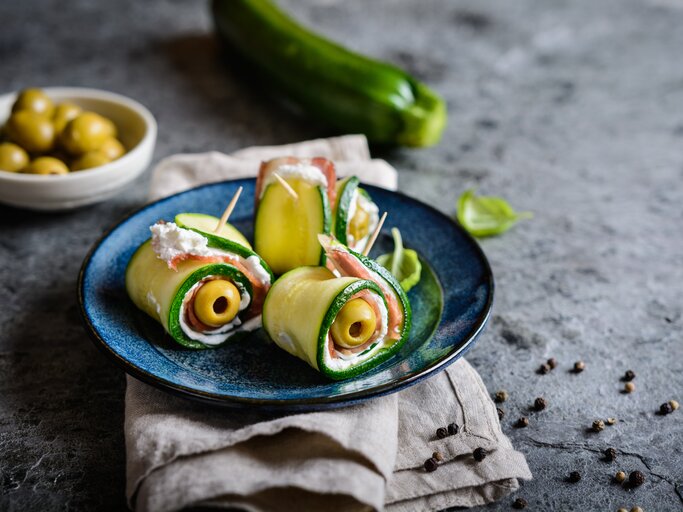 Gerollte Zucchini gefüllt mit Oliven, Schinken und Käse, fixiert mit einem Zahnstocher | © iStock.com/NoirChocolate