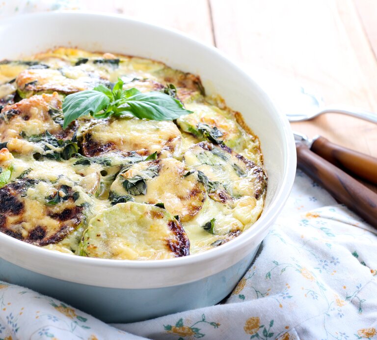 Zucchini-Auflauf mit Käse in blauer Auflaufform.  | © iStock/manyakotic