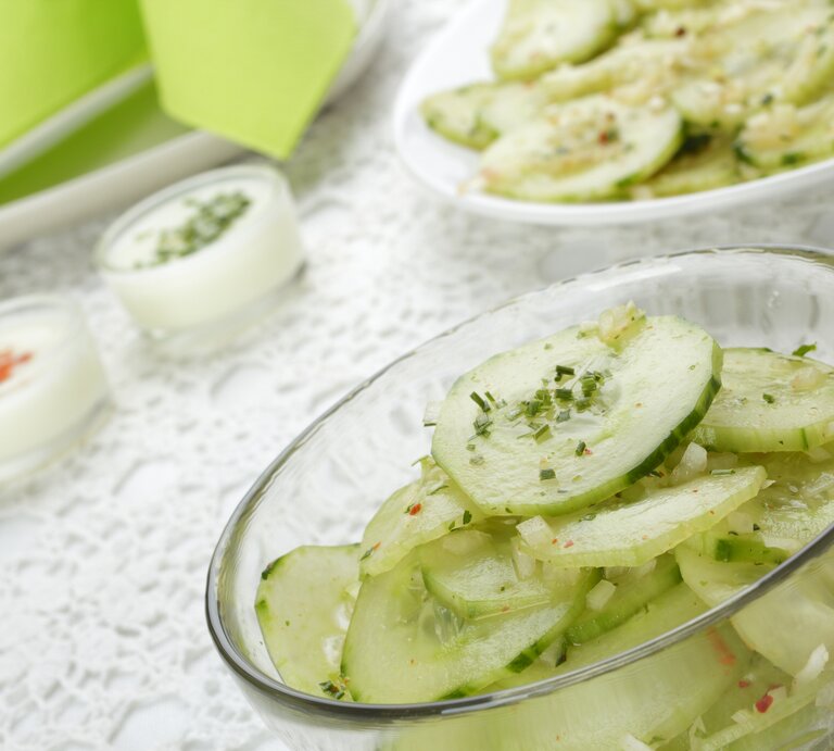 Schräge Seitenansicht auf eine Glasschale mit Gurkensalat mit durchsichtigem Dressing.  | © iStock/Atide