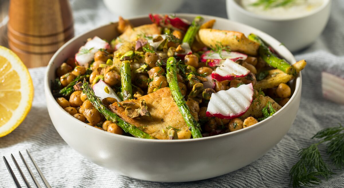 Sommerliche Aufnahme von einer Schüssel mit libanesischem Brotsalat mit gebratenen Spargel und Radieschen. 