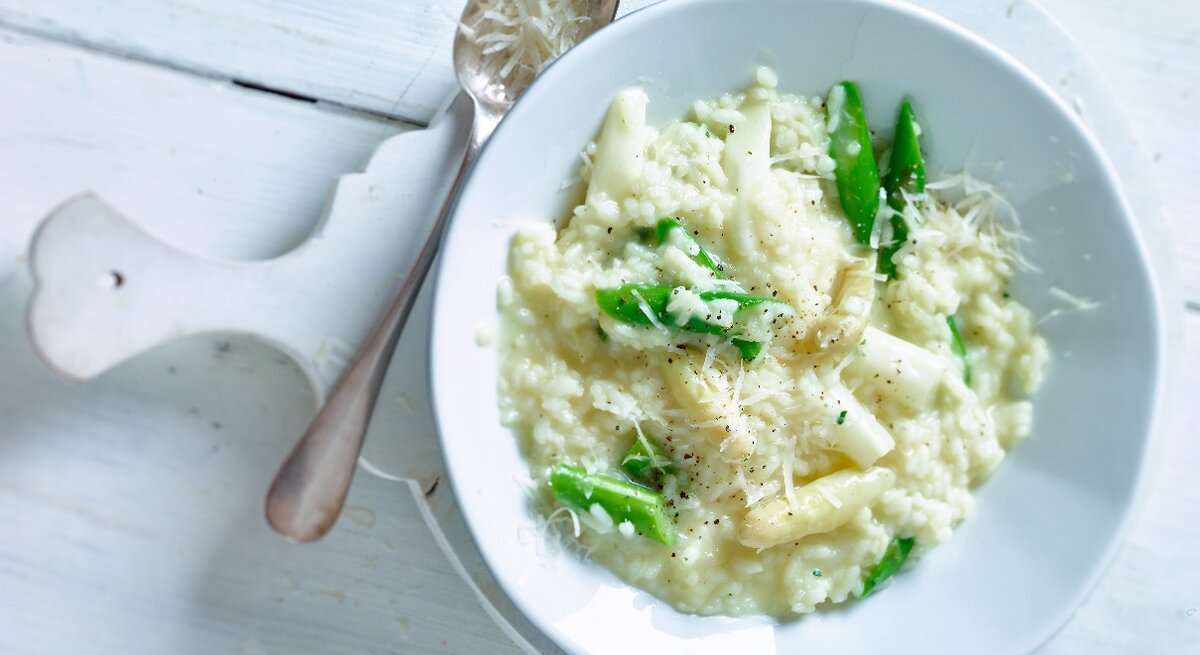 Cremiges Risotto mit grünem und weißem Spargel auf einem Teller.