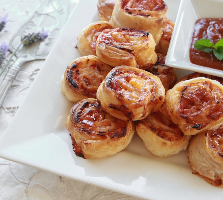 Mehrere Blätterteig-Schnecken mit Hawaii-Füllung auf einem weißen Teller.  | © iStock/ ThitareeSarmkasat