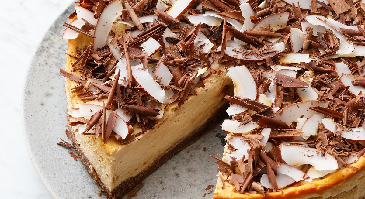 Der Kuchen mit einem ausgeschnittenen Stück auf einem grauen Teller von schräg oben fotografiert.