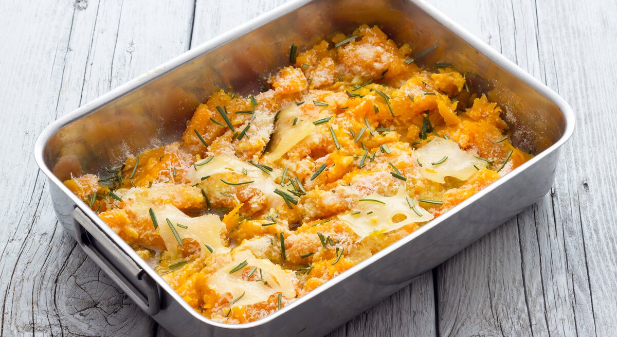 Blecherne Auflaufform gefüllt mit Kürbisauflauf und Parmesan.