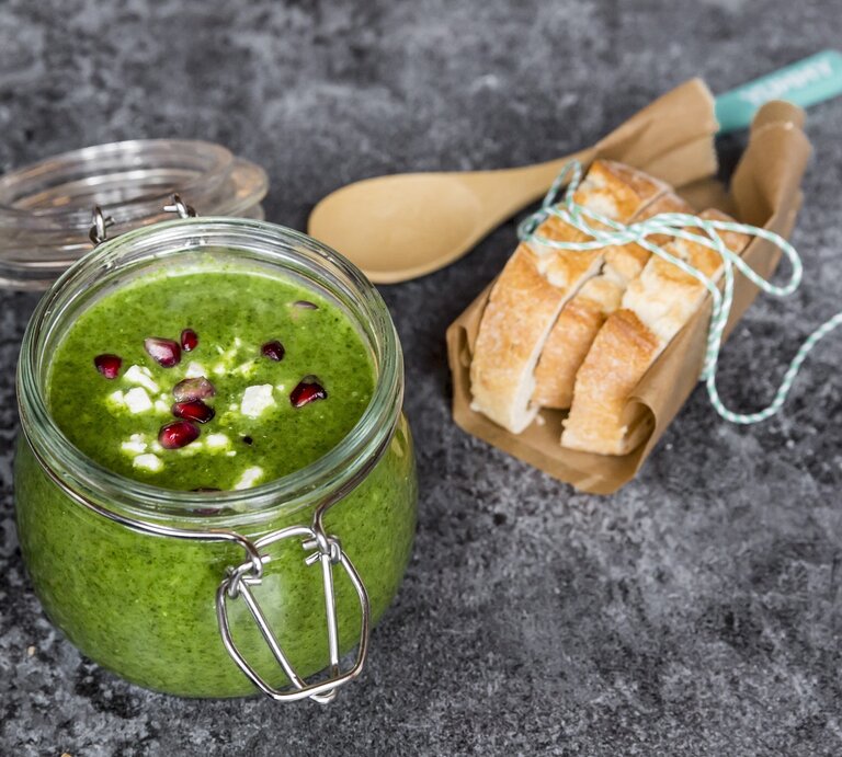 Grünkohlsuppe mit Granatapfel in einem Bügelverschlussglas vor rustikalem Hintergrund. Rechts Baguettte-Scheiben. Draufsicht. | © StockFood/Rsch,Sandra/FC