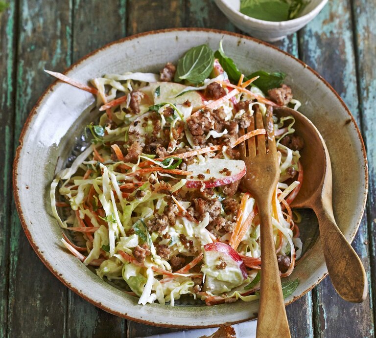 Möhren-Spitzkohl-Salat mit Rinderhack und Apfel / runder Teller / Löffel und Gabel aus Holz / Untergrund Holzplanken / Draufsicht, schräg | © StockFood / Hoersch, Julia