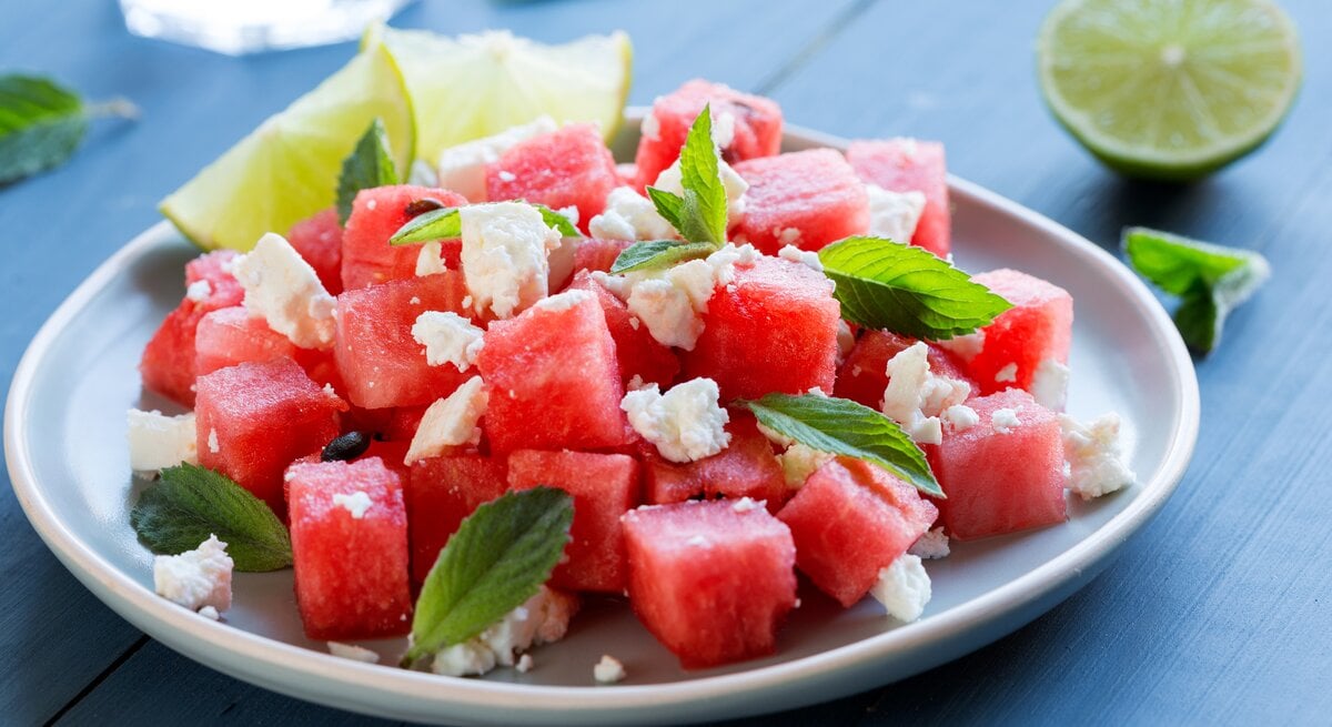 Ein Melonen-Feta-Salat auf einem Teller, stehen auf einem Tisch ist zu sehen.