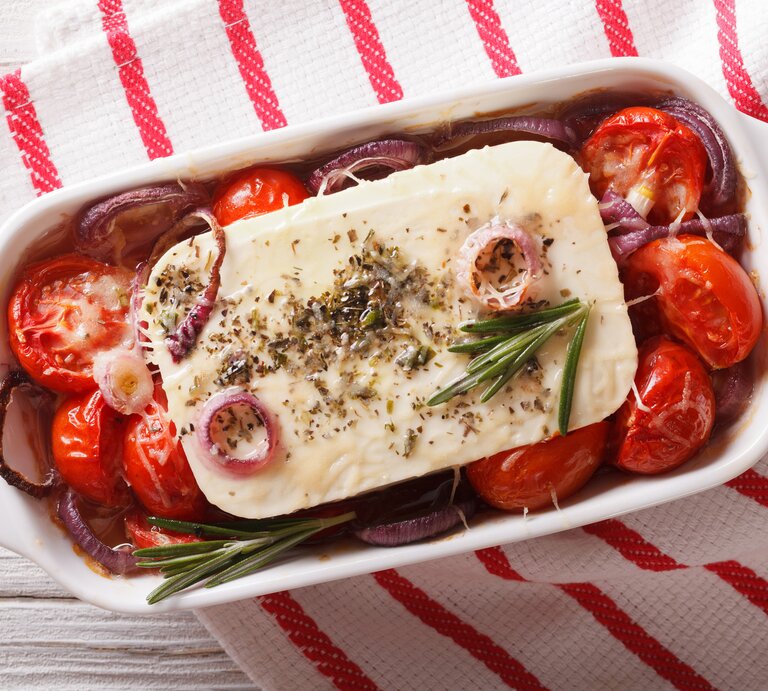 Draufsicht auf eine Auflaufform gefüllt mit gebackenem Feta, Tomaten, Rosmarin und roten Zwiebeln.  | © iStock/ ALLEKO