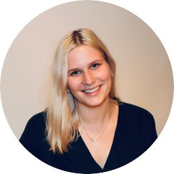 Das Bild zeigt eine junge Frau mit blonden Haaren, die in die Kamera lächelt. Sie trägt ein schwarzes Oberteil und eine Kette mit einem kleinen Anhänger. Ihr freundliches Lächeln und ihre offene Körperhaltung vermitteln eine positive und herzliche Ausstrahlung. Der Hintergrund ist neutral und unscharf, was den Fokus auf die Frau richtet. | © privat