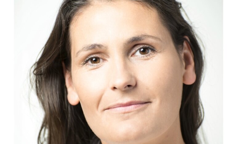 Das Bild zeigt eine Frau mit einem nachdenklichen und ruhigen Gesichtsausdruck. Sie hat lange, dunkle Haare und trägt ein weißes Oberteil mit einer feinen Halskette. Ihr Blick ist leicht nach oben gerichtet und sie scheint in die Ferne zu schauen. Der Hintergrund ist schlicht und hell, was die Aufmerksamkeit auf ihr Gesicht lenkt. | © privat