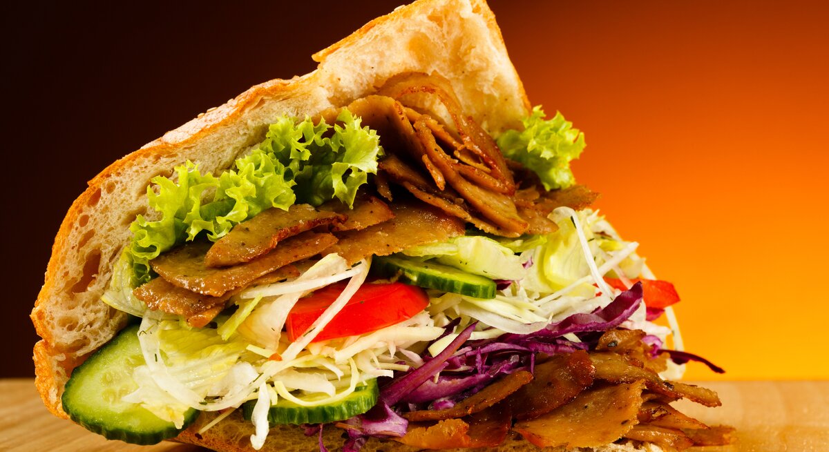 Ein leicht geöffnetes Fladenbrot mit typischer Döner-Füllung aus Fleisch und Salat. 