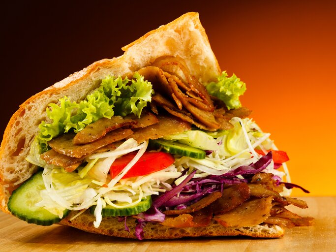 Ein leicht geöffnetes Fladenbrot mit typischer Döner-Füllung aus Fleisch und Salat.  | © iStock/gbh007