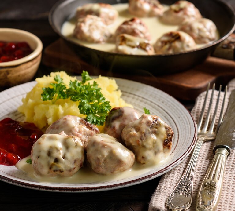 Rustikaler Teller mit Kartoffeln, Preiselbeersoße, Hackbällchen "Köttbullar" und cremiger Soße.  | © iStock/iko636